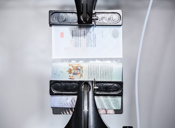 Un passeport est ouvert et fixé par une machine sur la ligne d'assemblage