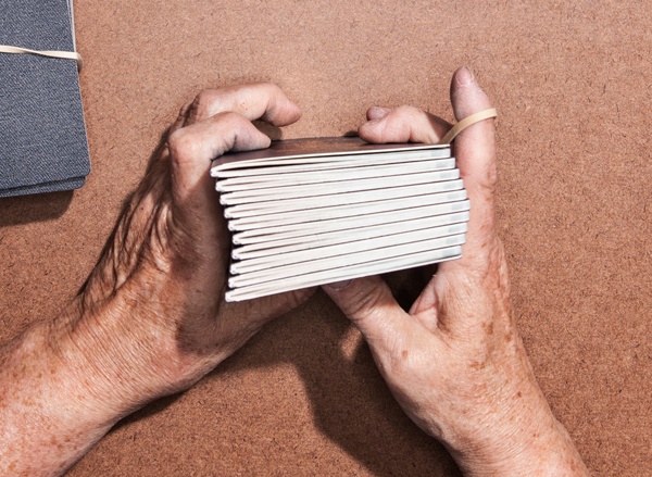 Man grips a stack of passports in hands ready to hold them together with elastic band