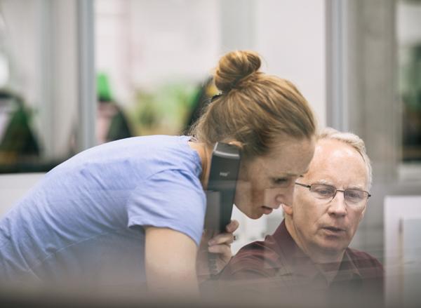 Une jeune employée de CBN téléphone depuis le poste de travail d’un de ses collègues