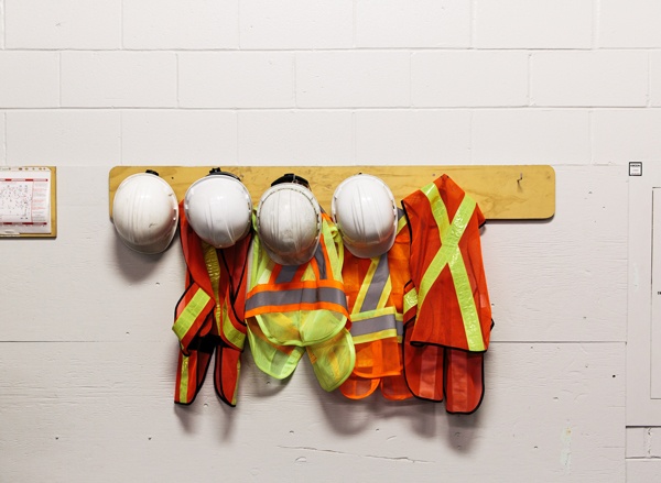 Cascos de protección y chalecos reflectantes colgados en un perchero