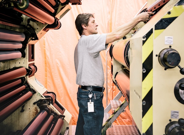 CBN male employee adjusts part of printing machine