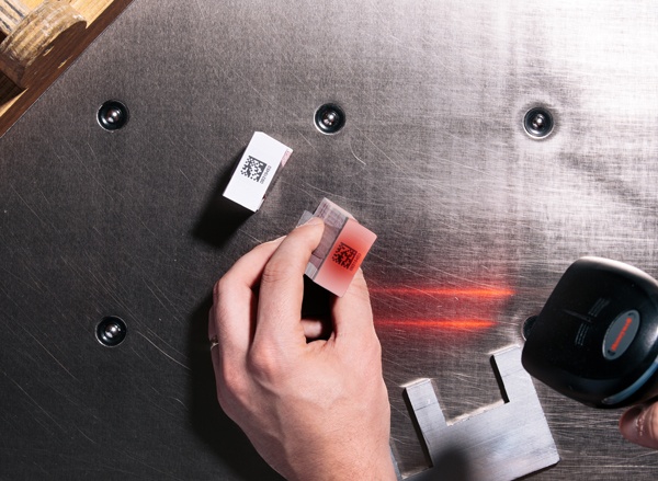 Man holds stack of excise stamp and scans QR code with red laser scanner