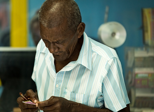 Hombre mayor de St. Lucia verifica su billete de lotería