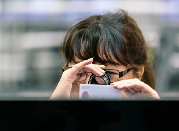 CBN female employee uses looking glass to examine certificate