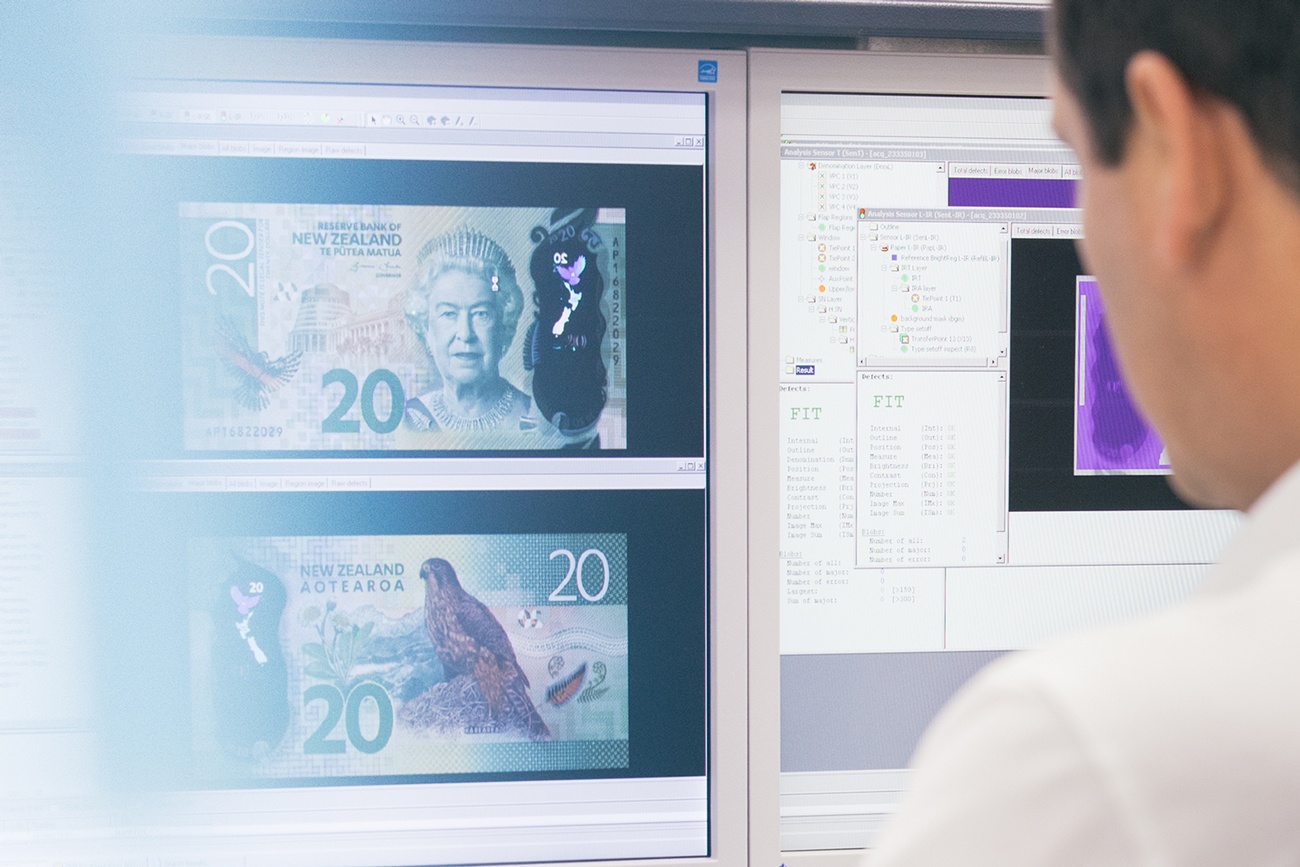 Un homme regarde un billet de 20 dollars néo-zélandais sur un écran d’ordinateur.